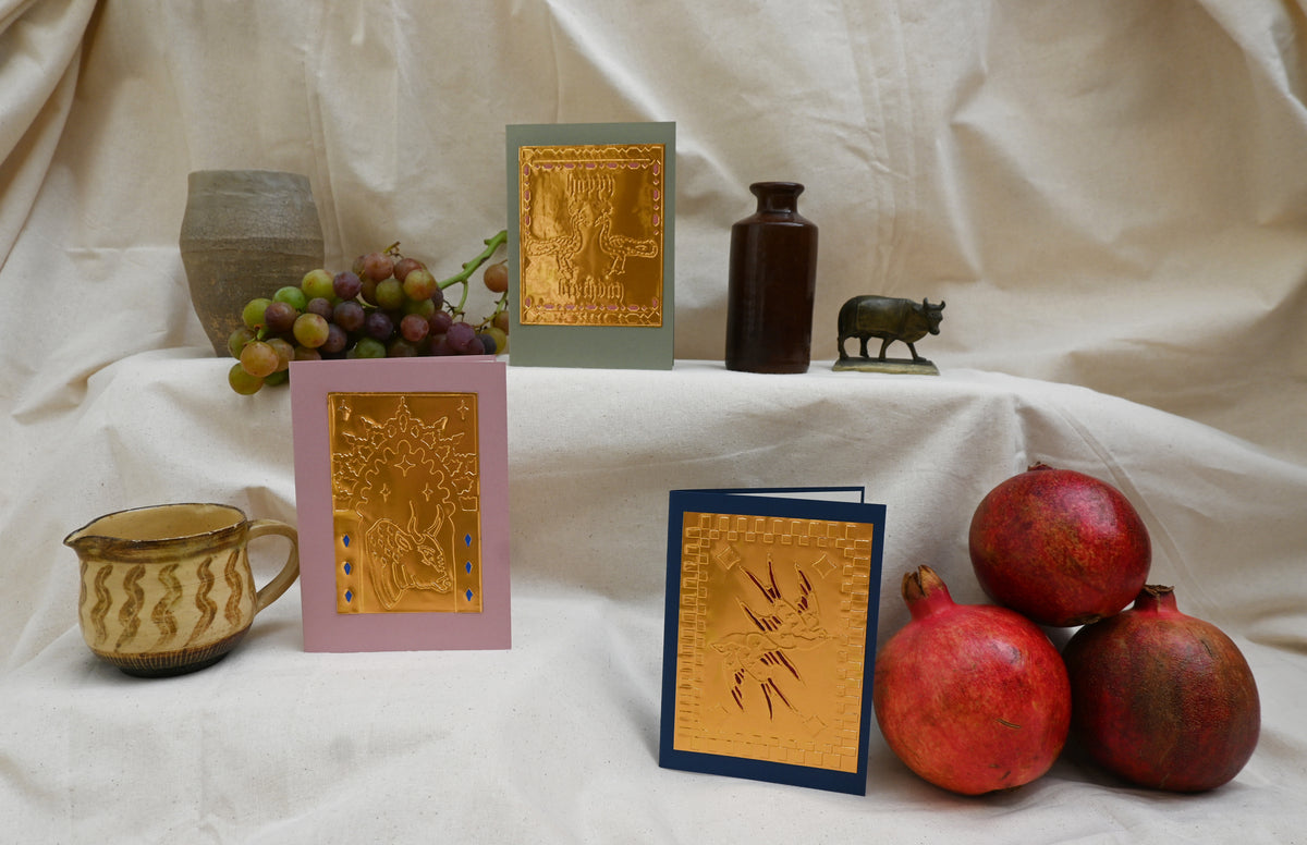 A collection of 3 greeting card by Fabler's Press. Navy blue with swallows. Dusty pink with Bull in archway design and green card with two peacocks and Happy Birthday message, surrounded by ancient looking pots and ceramics, pomegranates and a bunch of green blushing grapes. reminiscent of a Venetian still life on a back drop of cream canvas.
