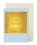 A greeting card by fabler's Press with a raised text design "New Beginnings" with and ornate border on a muted blue card stock, shown with a plain off-white envelope behind it on a white background.