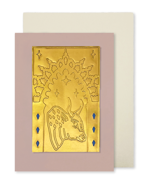 A greeting card with a dusty pink border and a gold foil illustration of a bull under an arch, shown with a cream envelope behind it on a white background.
