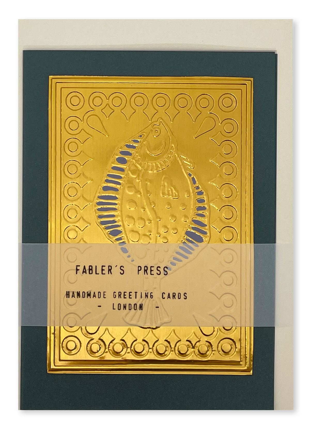 A handmade greeting card with a large embossed gold fish design on a dark green background, shown with a cream envelope behind it. A semi-transparent band across the lower middle reads 'FABLER'S PRESS HANDMADE GREETING CARDS - LONDON -'.