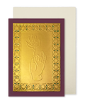 A gold-toned greeting card with a raised hand holding a flower motif, surrounded by an ornate patterned border, set against a deep burgundy background. A cream-coloured envelope is positioned behind the card.