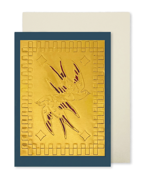 A navy blue greeting card with a raised gold foil panel of 2 swallows with red wings and a square motif border, shown with a cream envelope.