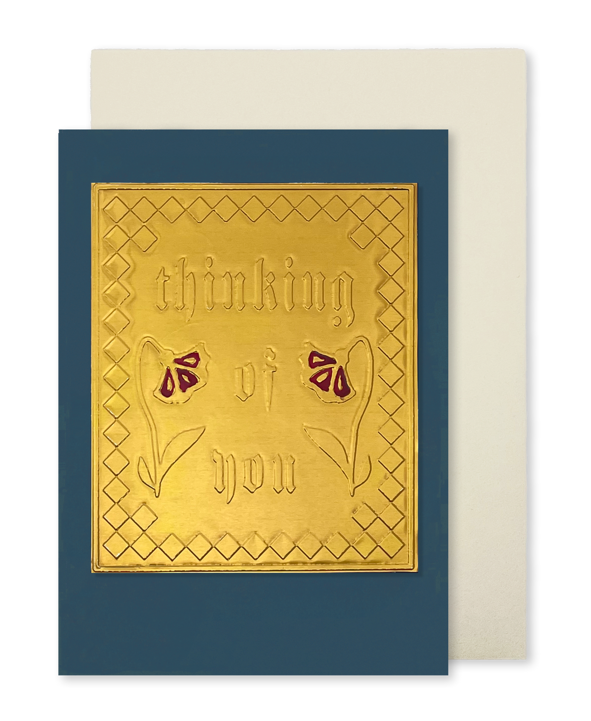 A navy blue greeting card with a raised gold foil panel reading 'thinking of you' and small red flower motifs, shown with a cream envelope 