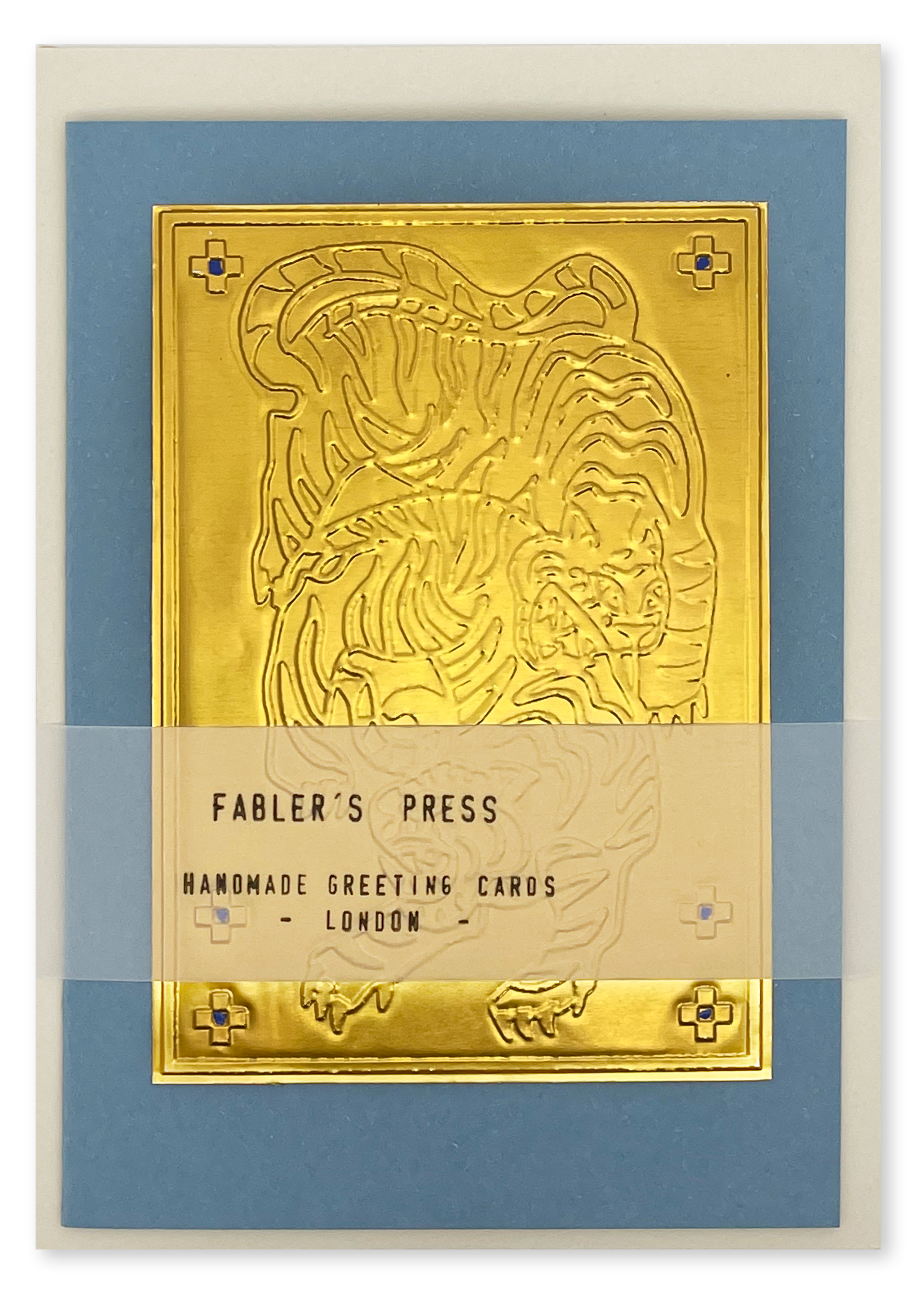 A handmade greeting card from Fabler's Press featuring an embossed gold tiger design on a blue cardstock background, wrapped with a translucent band labeled 'FABLER'S PRESS HANDMADE GREETING CARDS LONDON'.